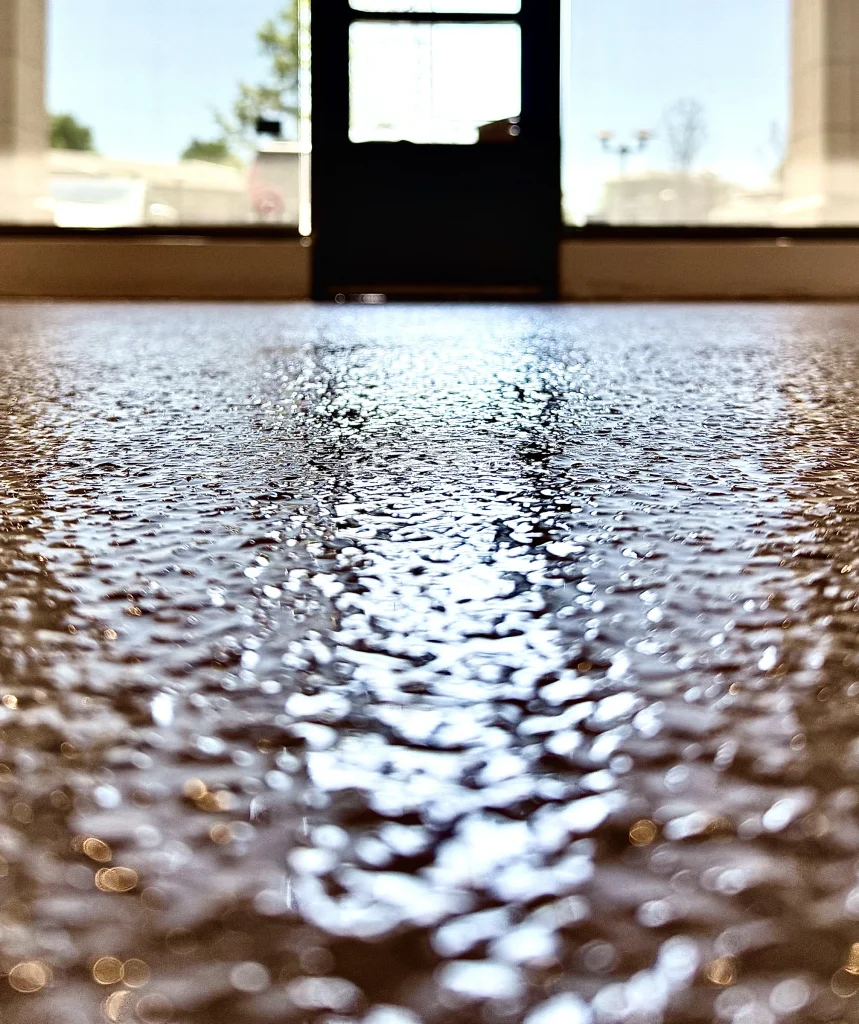 Low-angle close-up of the glossy tan flake floor at the storefront door